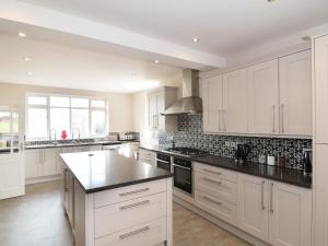 una gran cocina con armarios blancos y encimeras negras en Strelley Court Farm, en Heage