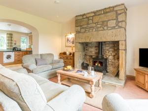a living room with a stone fireplace with couches and a table at Brian's Cottage in High Buston