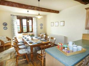 a dining room with a table and a kitchen at Street Head Farm in Cononley