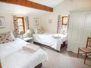 a bedroom with two beds and a chair at Street Head Farm in Cononley