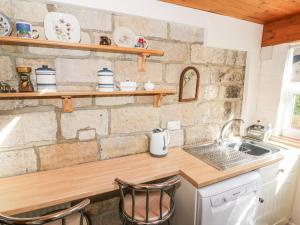 a kitchen with a sink and a stone wall at Lyndale Cottage in Robin Hood's Bay