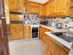 a kitchen with wooden cabinets and a sink at Ghyll Bank Bungalow in Staveley