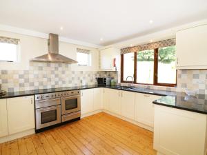 uma cozinha com armários brancos e um forno com placa de fogão em Ghyll Bank House em Staveley