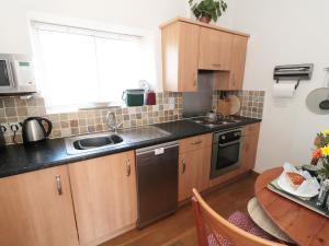 a kitchen with wooden cabinets and a table with a sink at Cobbled Corner in Elton