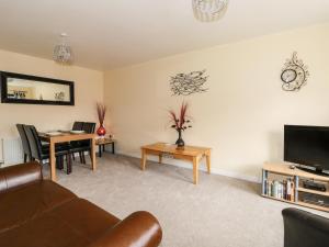 a living room with a couch and a table and a tv at Prince Cottage in Loftus