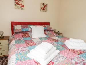 a bed with white towels on it with a quilt at Prince Cottage in Loftus
