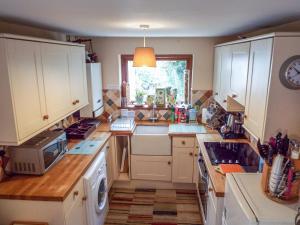 a kitchen with white cabinets and a sink at Lothlorien Cottage in Garnant