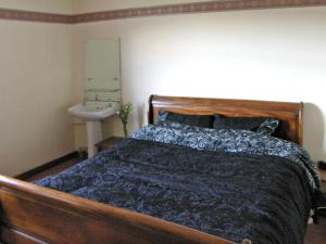 a bedroom with a wooden bed and a sink at Homestone Farm in Drumlemble
