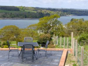 a table and chairs on a patio with a view of a lake at Ysgubor Penrallt in Y Felinheli