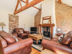 sala de estar con muebles de cuero y chimenea en Wheelhouse Cottage, en Bagby