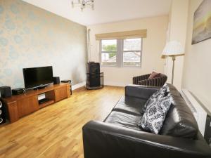 a living room with a couch and a flat screen tv at William Court Cottage in Santon Bridge