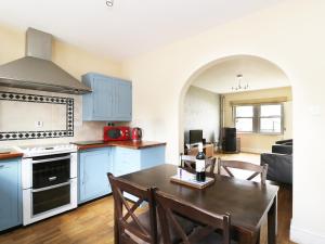 a kitchen with blue cabinets and a table with chairs at William Court Cottage in Santon Bridge