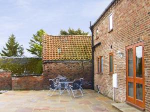 a patio with a table and chairs next to a brick building at Croft Granary in Stillington