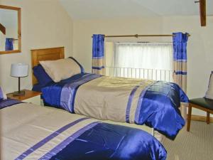 a bedroom with two beds with blue and white sheets at Croft Granary in Stillington