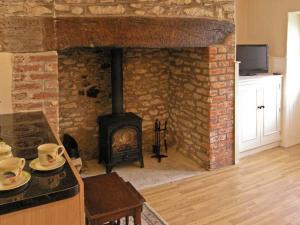 a living room with a brick fireplace with a stove at Candy Cottage in Bradford Abbas