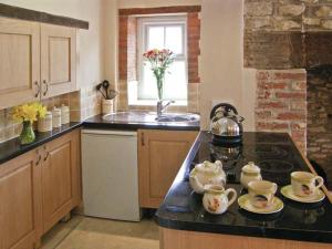 a kitchen with a sink and a counter top with tea cups at Candy Cottage in Bradford Abbas