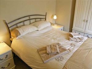 ein weißes Bett mit Handtüchern darauf in einem Schlafzimmer in der Unterkunft Candy Cottage in Bradford Abbas