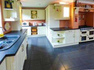 een grote keuken met witte kasten en een tegelvloer bij La Cala in Penderyn