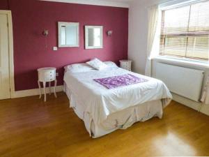 een slaapkamer met een groot bed met een paarse muur bij La Cala in Penderyn