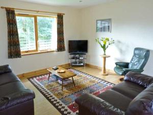 a living room with a leather couch and a television at Bruach Gorm Cottage in Grantown on Spey