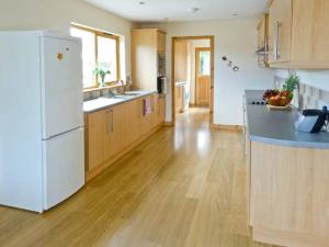 a kitchen with a white refrigerator and a wooden floor at Bruach Gorm Cottage in Grantown on Spey