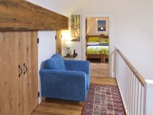 a blue chair in a room with a bedroom at Spingle Barn in Monyash