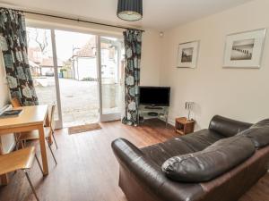 een woonkamer met een leren bank en een televisie bij No 3 Low Hall Cottages in Scalby