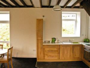 une cuisine avec des placards en bois, une table et une table dans l'établissement Hendre Aled Cottage 3, à Llansannan