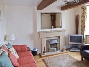 a living room with a red couch and a fireplace at Heathylee in Longnor