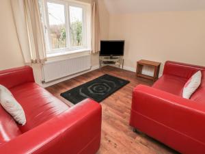 a living room with two red couches and a television at No 2 Low Hall Cottages in Scalby