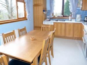 a kitchen with a wooden table and chairs in it at Laxdale Cottage in Banavie