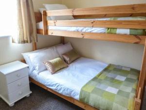 a bedroom with two bunk beds and a night stand at Oyster Catcher in Mainsriddle