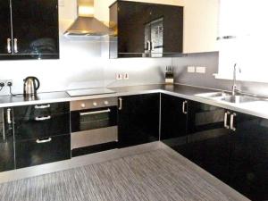 a kitchen with black cabinets and a sink at Braewood in Invermoriston