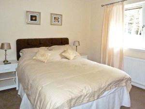 a white bed in a bedroom with a window at Braewood in Invermoriston