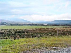 a field with a fence and mountains in the background at Braewood in Invermoriston