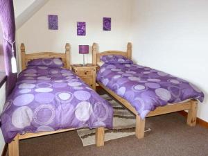 two beds in a room with purple comforter at Pool House in Midtown Brae