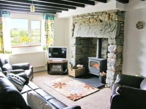 a living room with a couch and a stone fireplace at Bryn Re in Trawsfynydd