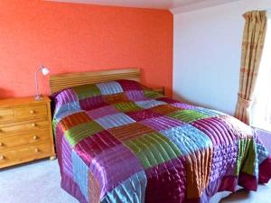 Un dormitorio con una cama colorida y un tocador de madera. en The Crook en Great Urswick