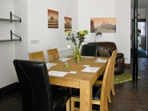 a wooden table with chairs and a vase of flowers on it at The Reiver's Retreat in Haltwhistle