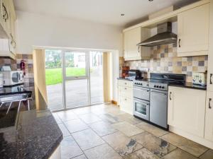 a kitchen with white cabinets and a stove top oven at Ghyll Bank Byre in Staveley
