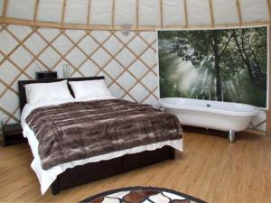 ein Schlafzimmer mit einem Bett, einer Badewanne und einem großen Fenster in der Unterkunft Lakeview Yurt in Beckford