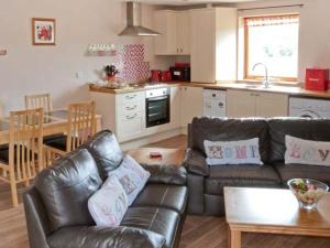 a living room with a leather couch and a kitchen at Cooper Cottage in Potto
