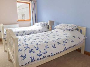 a bedroom with two beds with blue and white covers at Cooper Cottage in Potto