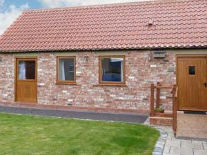 a brick house with a red roof and a yard at Cooper Cottage in Potto