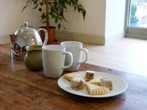 a plate of food on a wooden table with two cups at Muirmailing Cottage in Plean