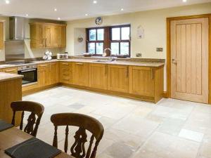 a large kitchen with wooden cabinets and a table and chairs at Orcaber Cottage in Austwick