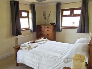 a bedroom with a white bed with two towels on it at Hartam House in Falstone