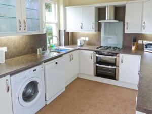 a kitchen with white cabinets and a washing machine at Priory View in Bardsea