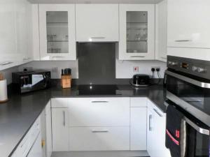 a kitchen with white cabinets and black appliances at Lillieput Lodge in Melbourne