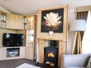 a living room with a wood stove and a tv at The Four Oaks Chalet in Fassfern